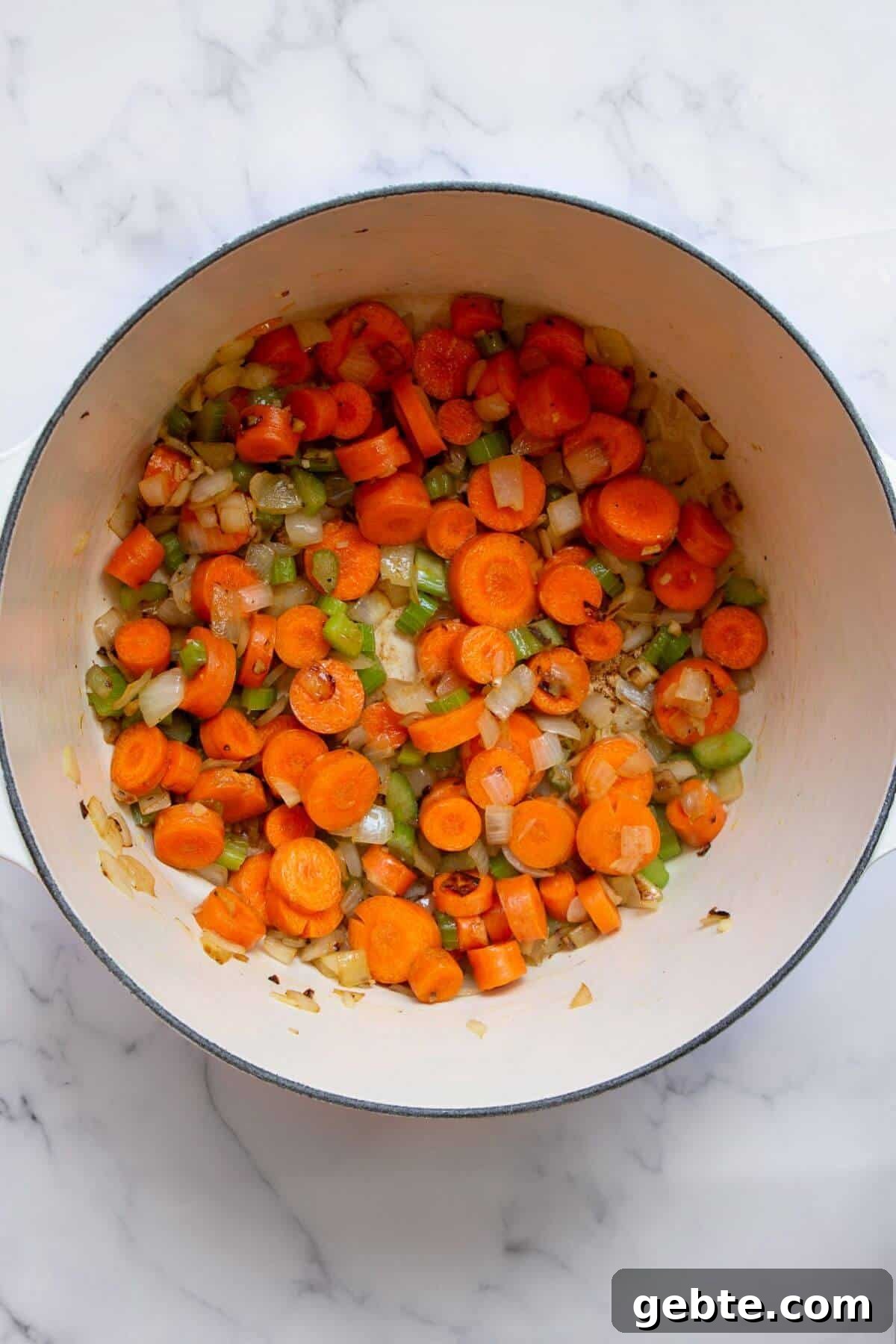 Creamy Carrot & Butternut Squash Soup Recipe for Fall Nights 6 Adding sliced carrot rounds into the pot with sautéed onions and celery.