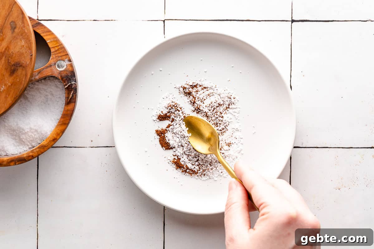 spoon mixing chipotle powder and salt together on a plate
