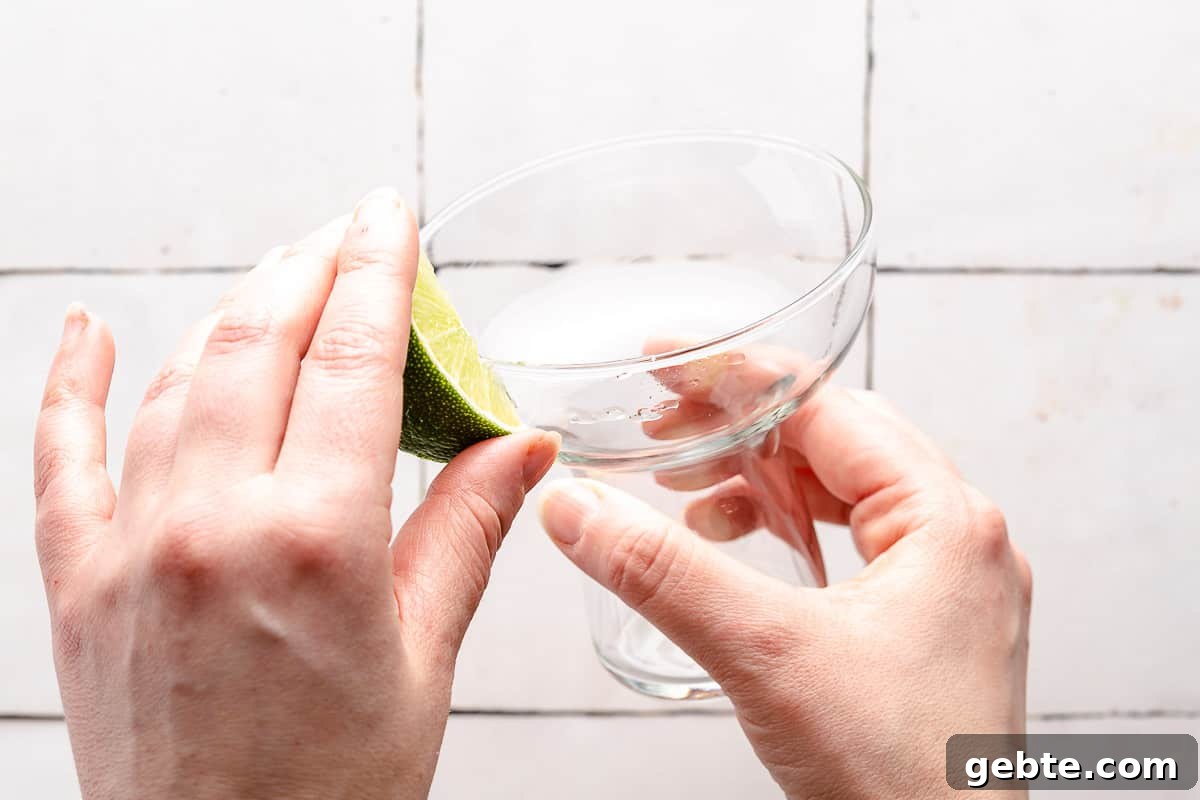 wedge of lime being rubbed on rim of glass