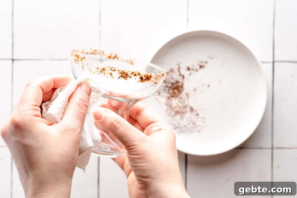 paper towel being used to clean edge of salt rim on glass
