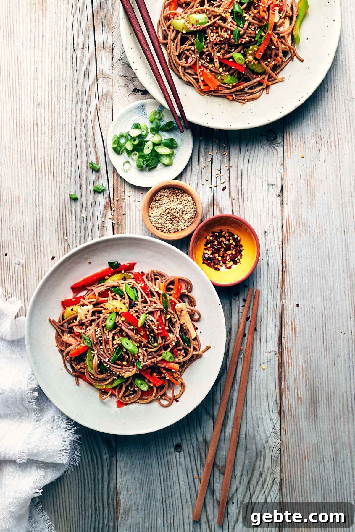 Table scene of two sesame soba noodle bowls on a white table