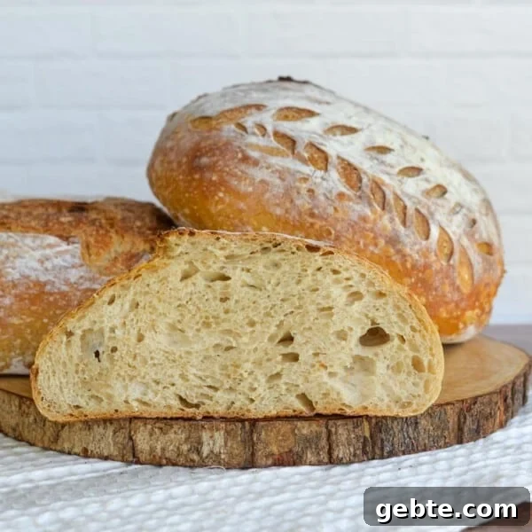 Sourdough Schedule for Beginners: Fit Baking into Your Daily Routine 13 Sourdough bread loaf with golden crust and decorative scoring, sliced to show soft interior crumb on a wooden board.