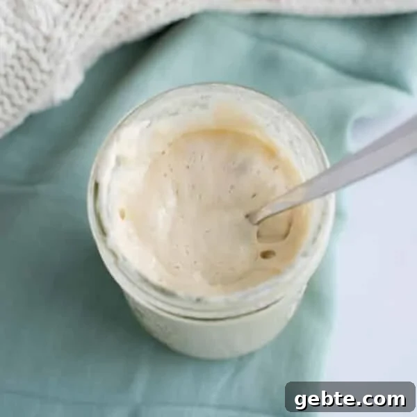 Sourdough Schedule for Beginners: Fit Baking into Your Daily Routine 10 Jar of active sourdough starter with a spoon showing a smooth, bubbly texture.