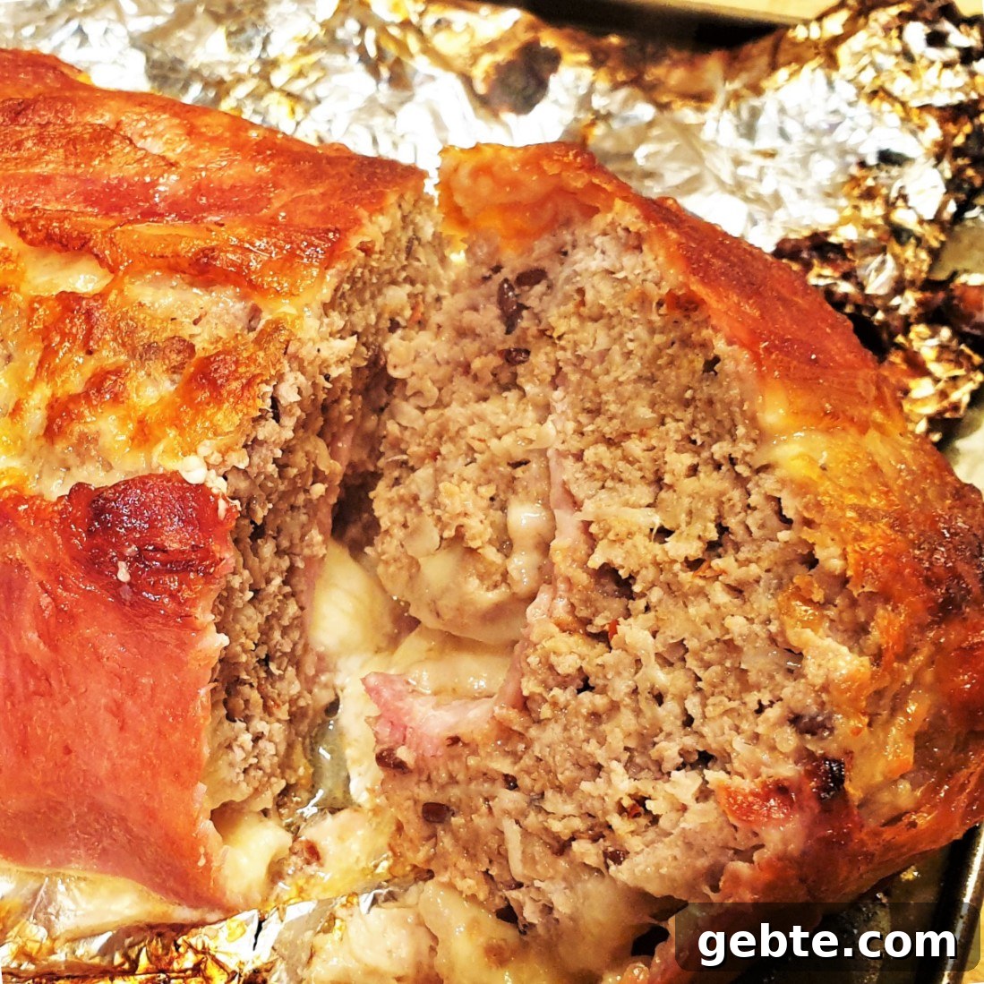 Bacon-Wrapped Meatloaf with Homemade Tomato Sauce 2 A cooked bacon covered meatloaf on tinfoil.