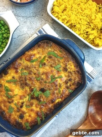 A blue serving dish of bobotie next to yellow rice.