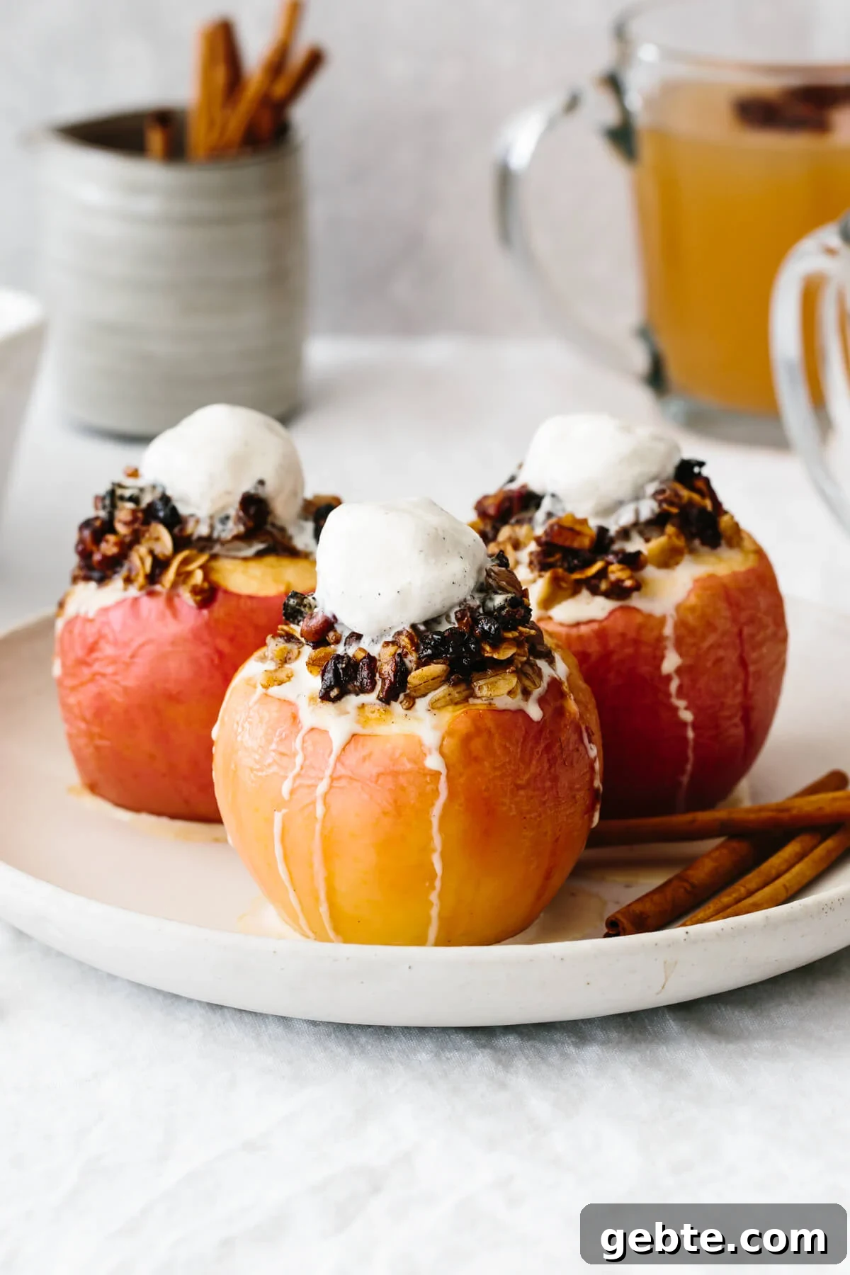 Three baked apples on a plate with melted ice cream on top.