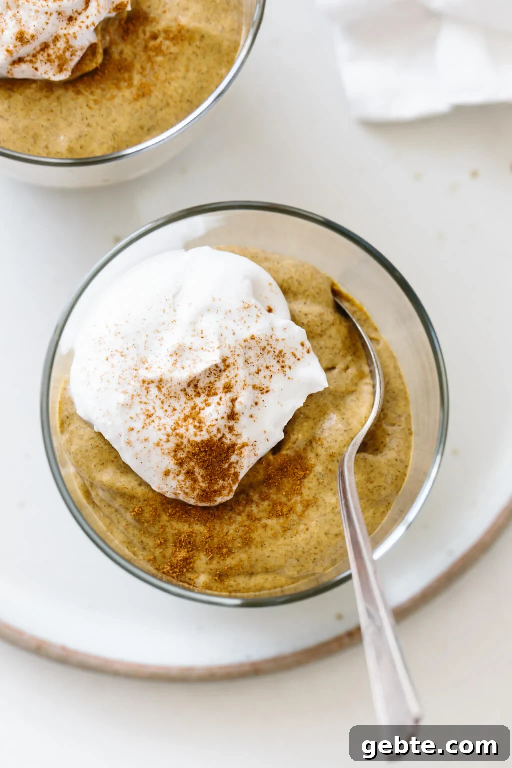Pumpkin chia pudding in a glass jar with a dollop of whipped cream and cinnamon.