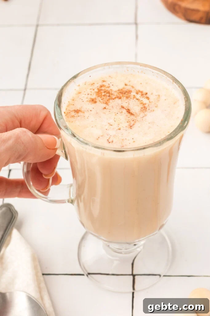 How to Make Hot Buttered Rum Mix at Home 5 hand holding a glass filled with hot buttered rum mix