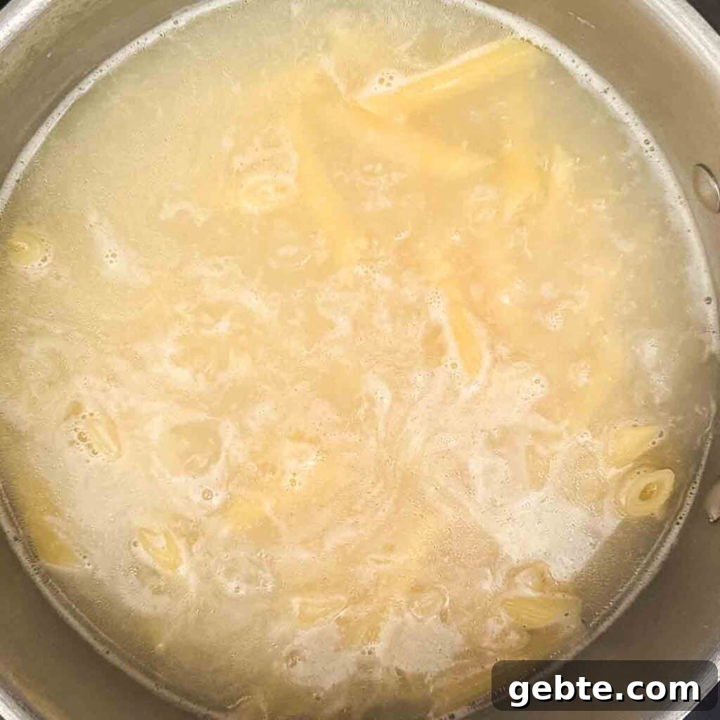 Boiling pasta in a large pot of salted water until al dente, with steam rising from the pot.
