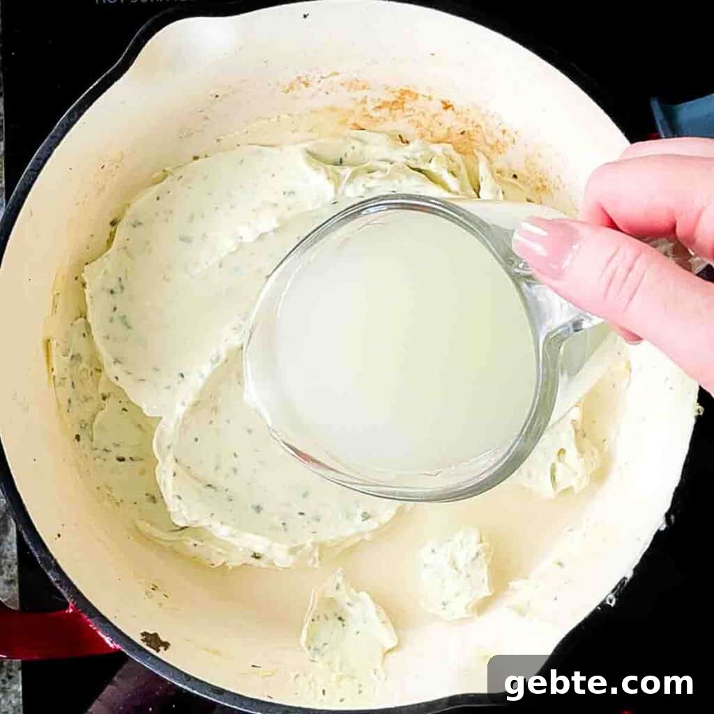 Cooking minced garlic in a skillet, then stirring in reserved pasta water to the Boursin cheese until it melts into a creamy sauce.