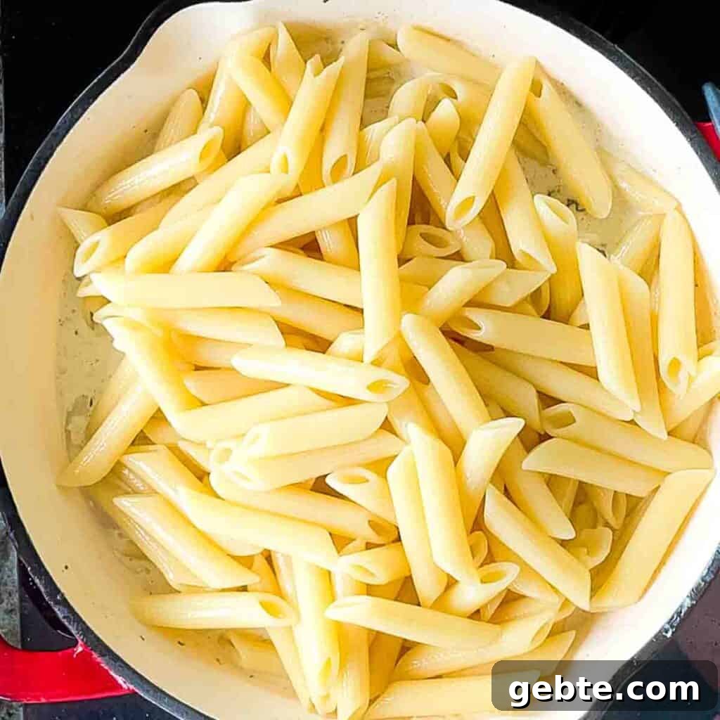 Tossing cooked pasta with the creamy Boursin cheese sauce and sautéed morel mushrooms in a large skillet.