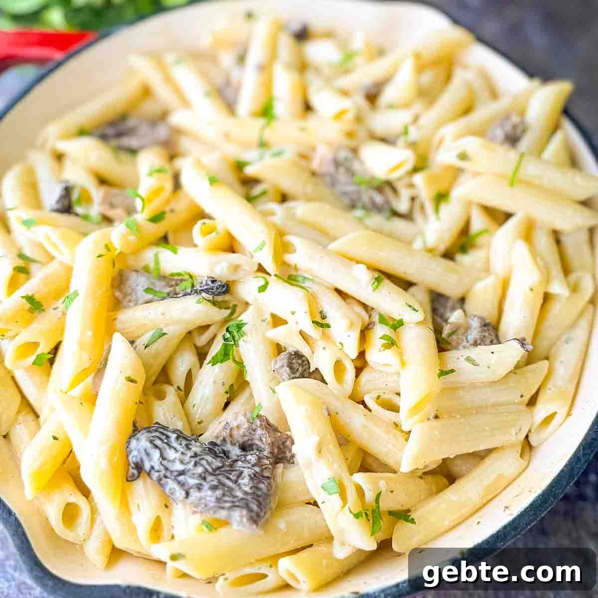 A large skillet filled with creamy Morel Mushroom Pasta, garnished with fresh parsley, ready to be served.