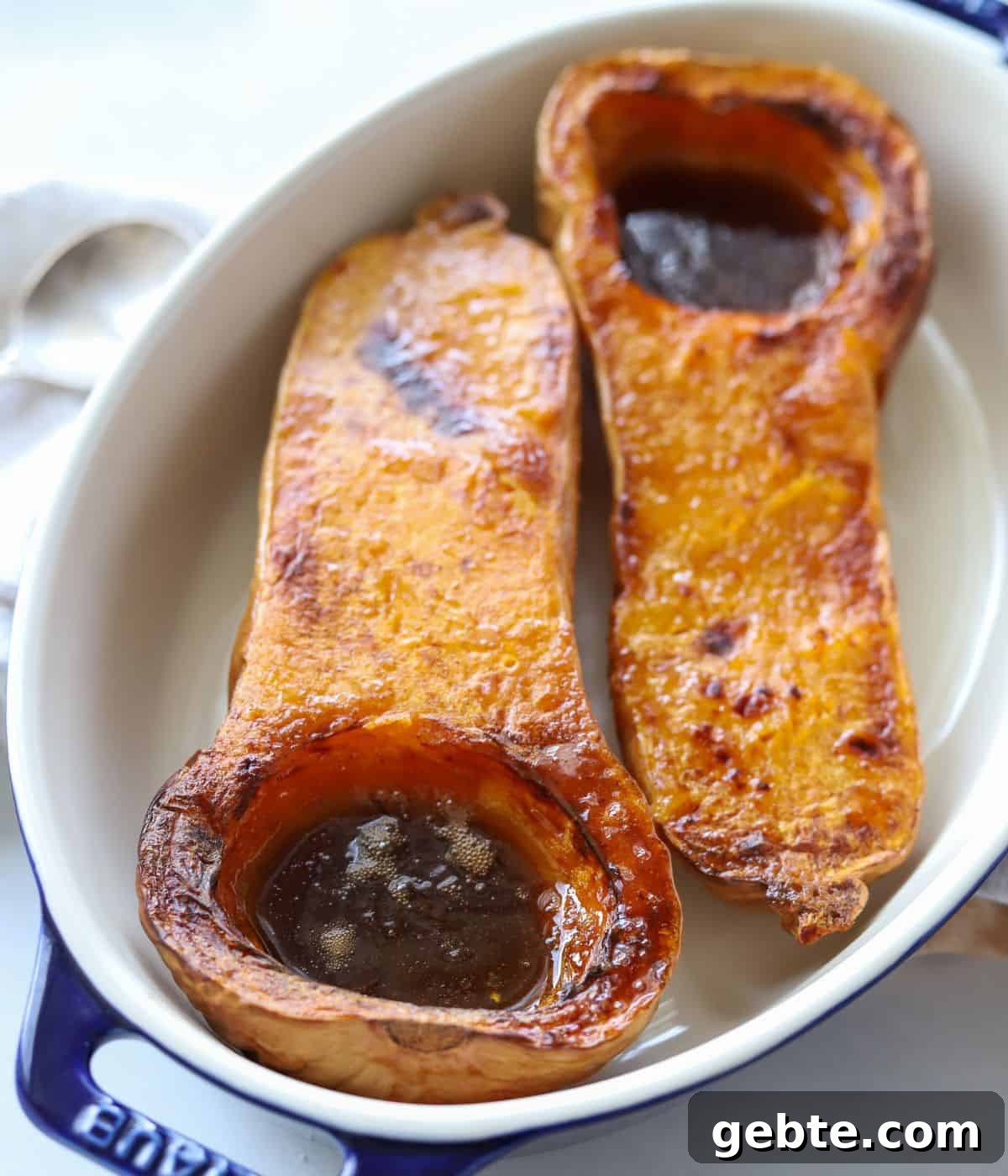 halved butternut squash in casserole dish filled with brown sugar butter mixture
