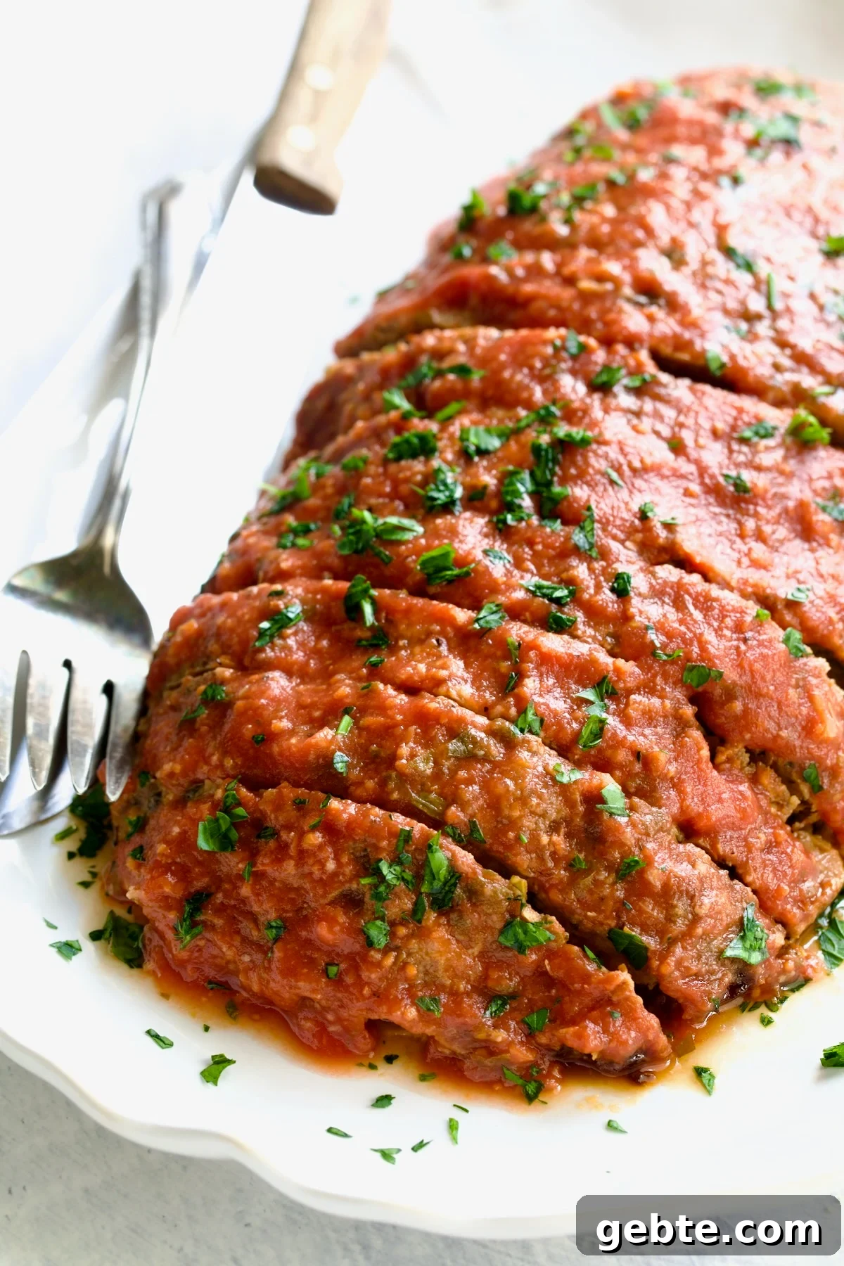 Italian Meatloaf on white platter with serving utensils.