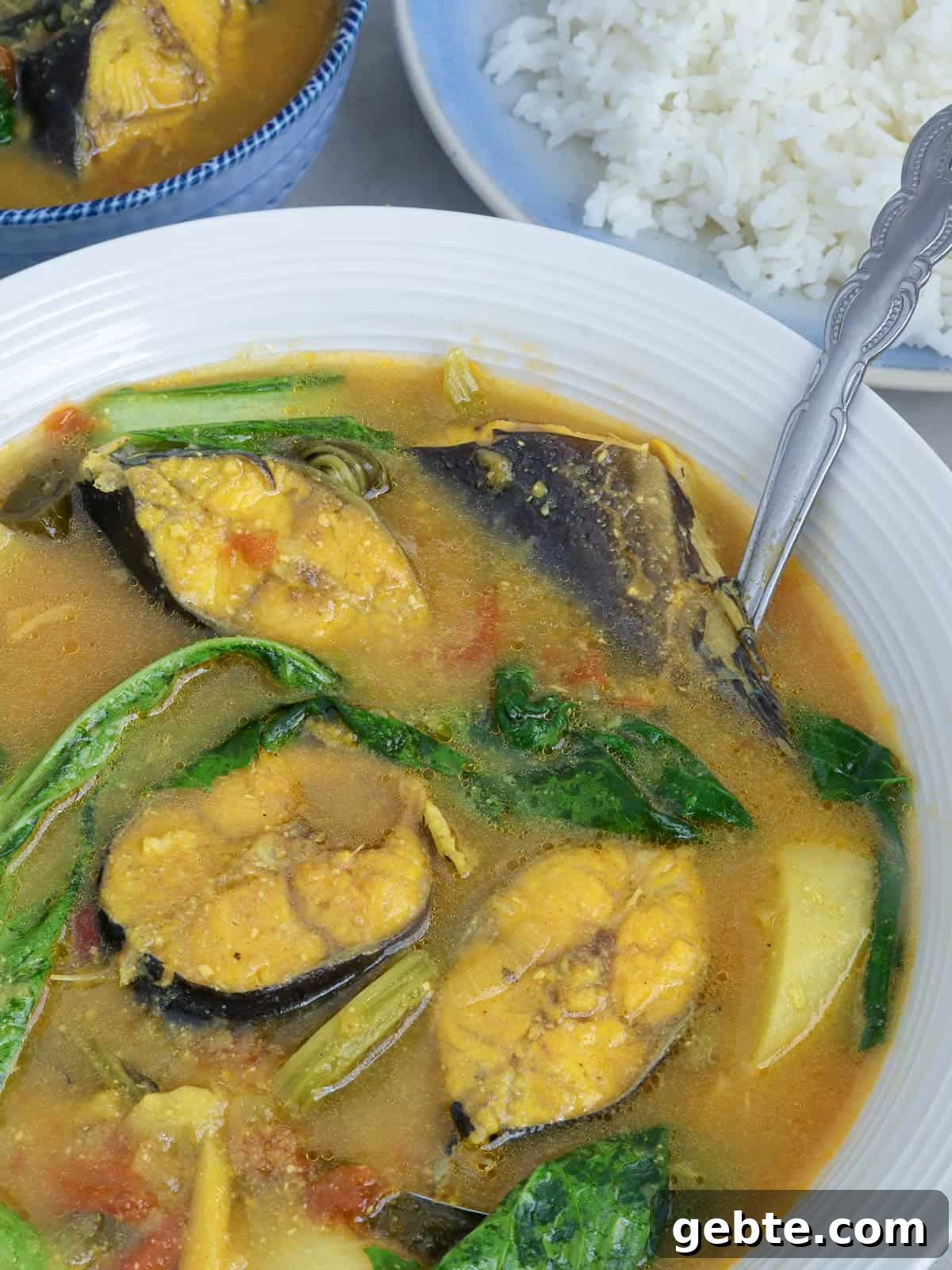 catfish sinigang with miso and mustard leaves in a white serving bowl