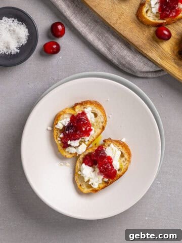 A close-up of cranberry and goat cheese crostini on a small plate.