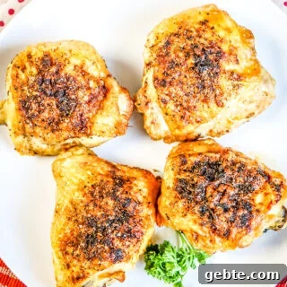 Crispy Air Fryer Chicken Thighs Recipe in 25 Minutes 6 Four Cooked Chicken Thighs on white plate on top of red plaid napkin