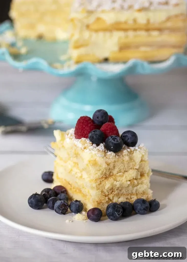 Limoncello Tiramisu Recipe: Bright Citrus Italian Dessert 3 A slice of tiramisu garnished with berries in front of the rest of the tiramisu on a cake stand