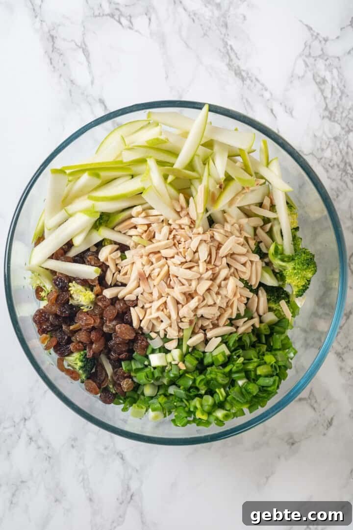 Overhead view of ingredients for broccoli slaw in bowl before tossing