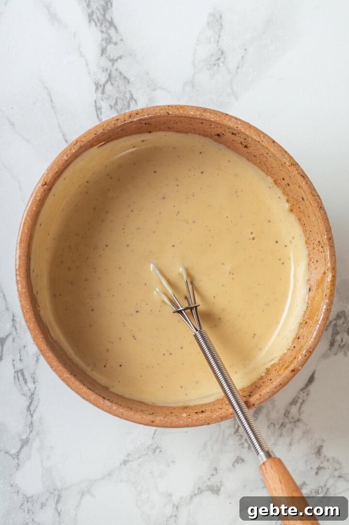 Overhead view of broccoli slaw dressing in bowl with whisk