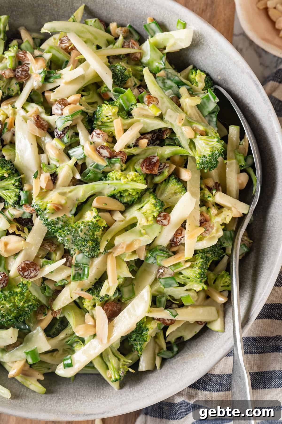 Overhead view of broccoli slaw in serving bowl with spoon