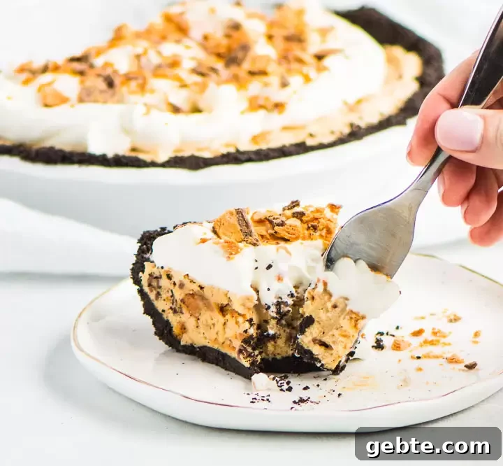 Decadent Butterfinger Pie Recipe: Chocolate-Peanut Butter Layered Pie 8 slice of pie on a plate with the rest of the pie in the background and a hand reaching in with a fork to take a bite