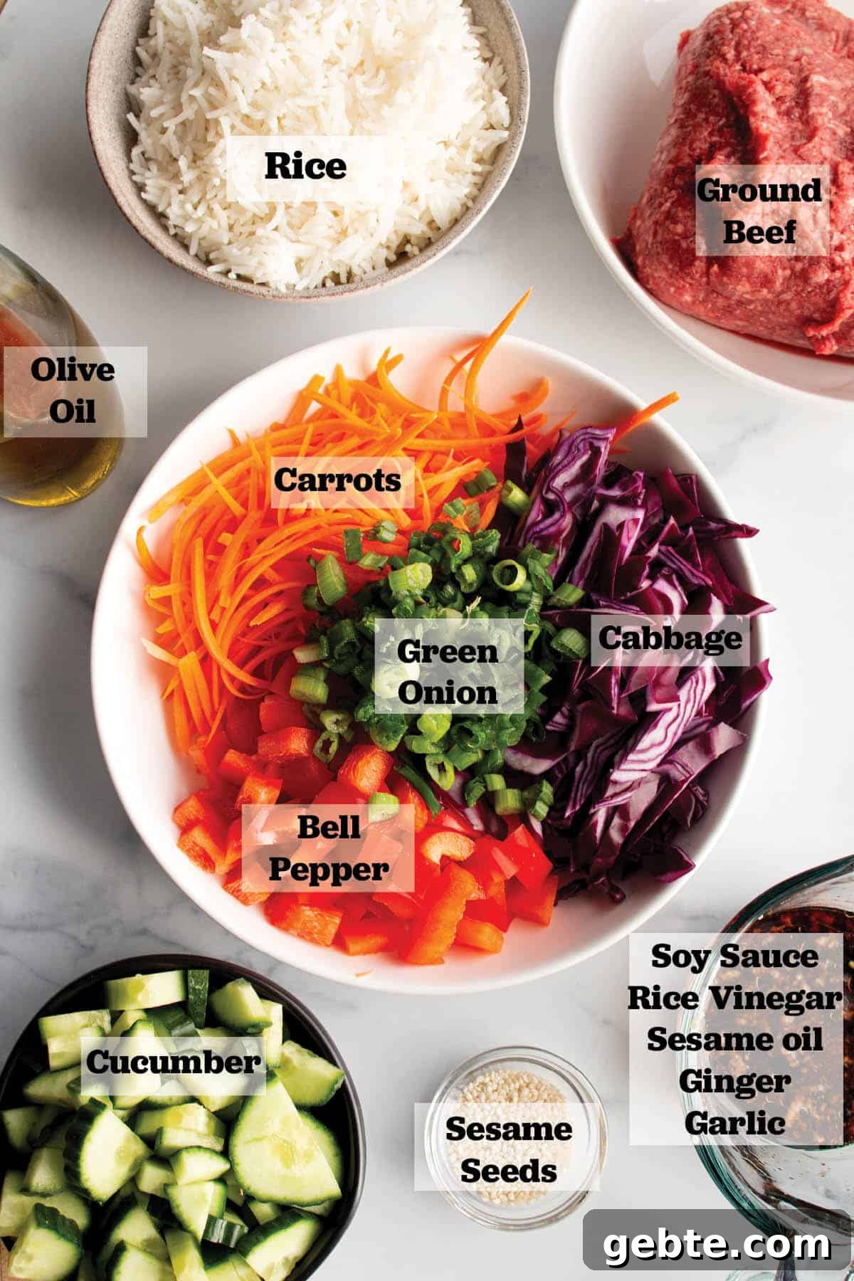 Ingredients in prep bowls. Ground beef, Cooked rice, olive oil, cucumbers, sesame seeds, a soy sauce mix, and a bowl of julienne carrots, chopped peppers, cabbage and green onions. 