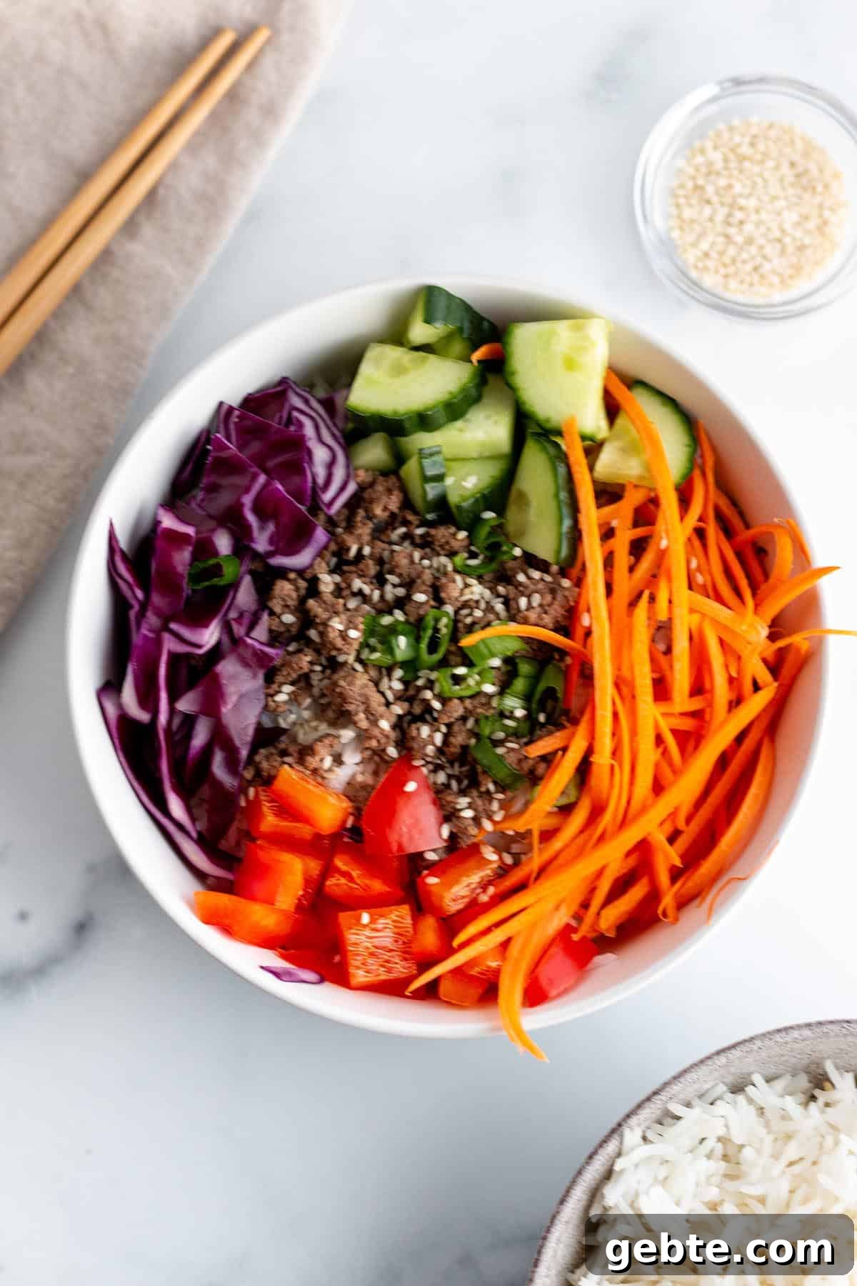 A bowl with julienne carrots, chopped peppers, cabbage, and green onion.