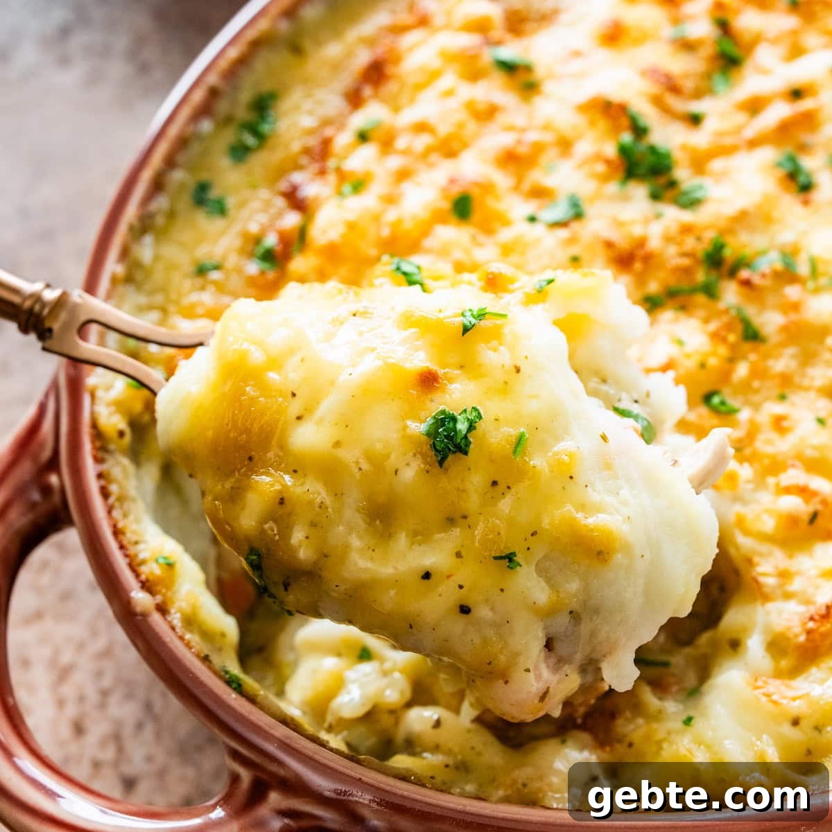 Hearty Turkey Shepherd's Pie Recipe for Comforting Weeknight Dinners 2 serving spoon dishing out a spoonful of turkey shepards pie from casserole dish.