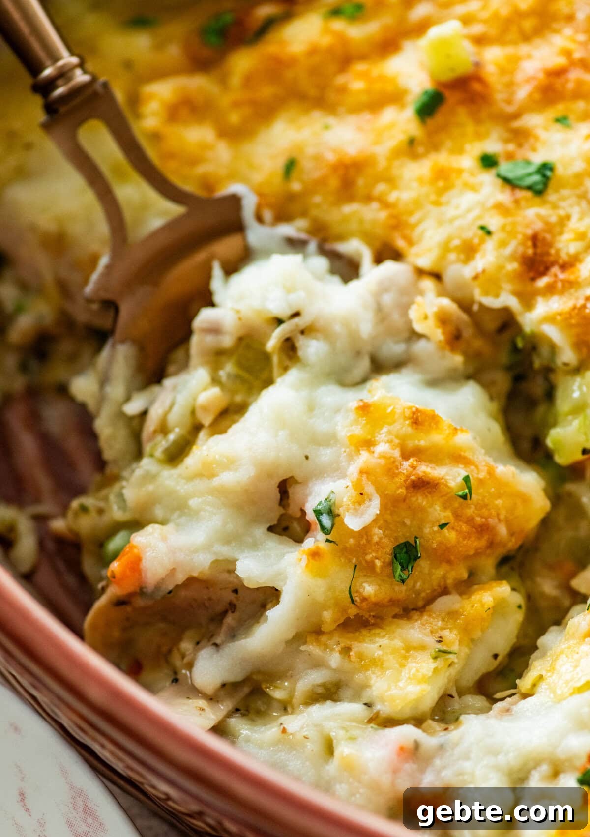 Hearty Turkey Shepherd's Pie Recipe for Comforting Weeknight Dinners 14 serving spoon dishing out a spoonful of turkey shepards pie from casserole dish.