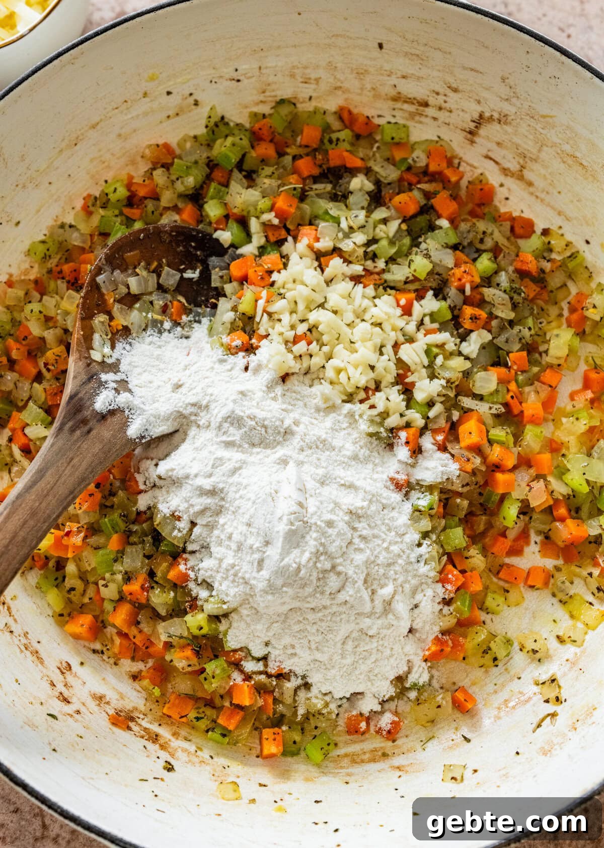 Hearty Turkey Shepherd's Pie Recipe for Comforting Weeknight Dinners 7 diced carrots, onions, celery, and flour with spices in a pot.