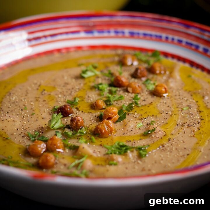 A bowl of potato and white bean soup topped with crispy chickpeas.
