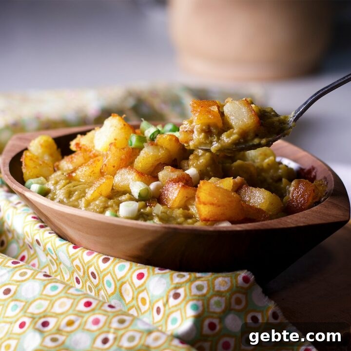 Someone lifting a spoonful of split pea soup from a wood bowl.