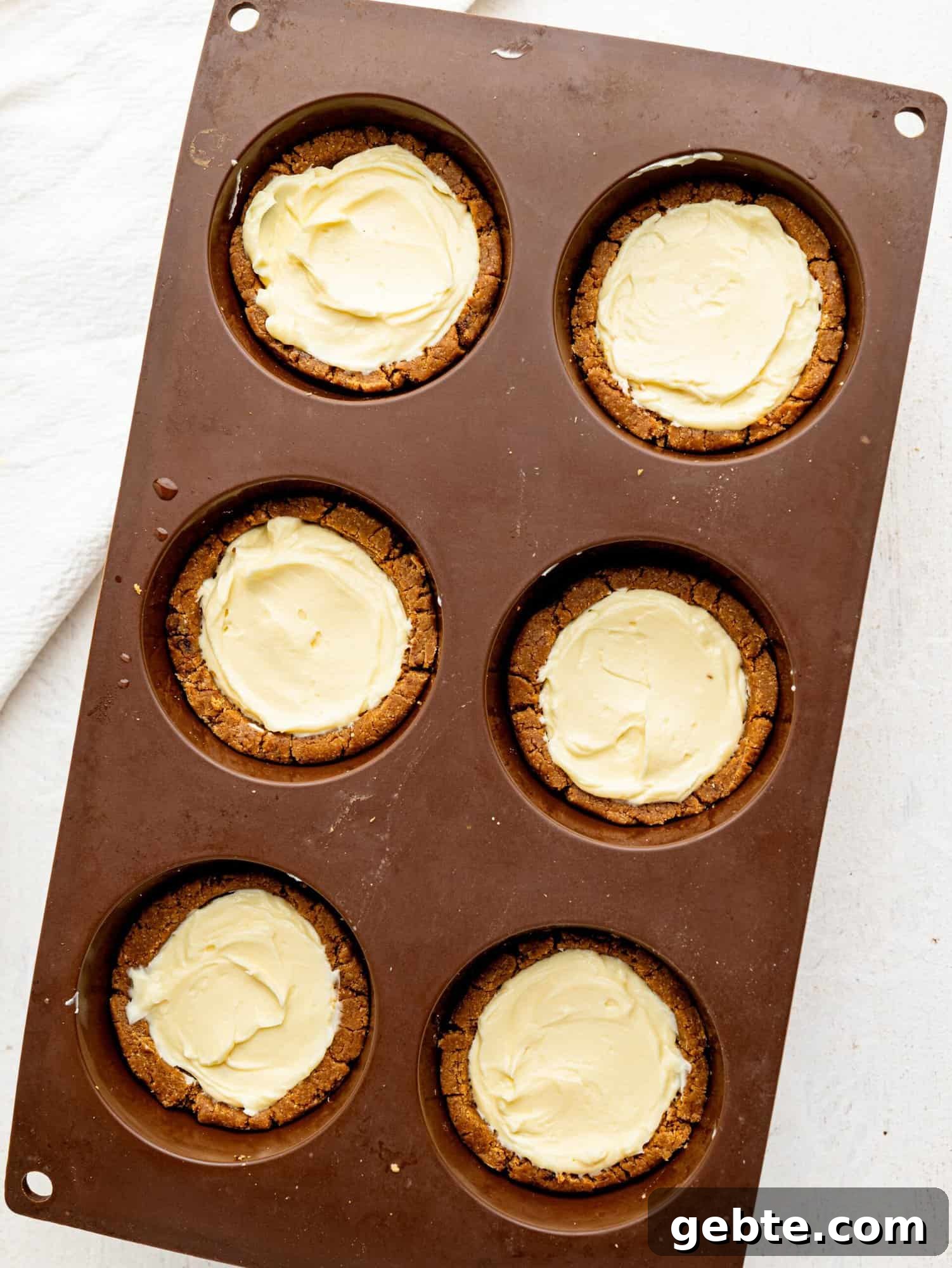Tiramisu cookie dough cups in a silicone muffin tray before dusting cocoa powder on.