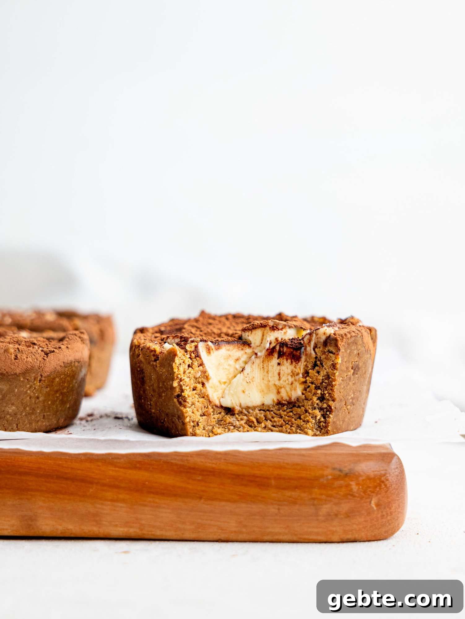 A half-eaten Three Tiramisu cookie dough cup on a wooden board.