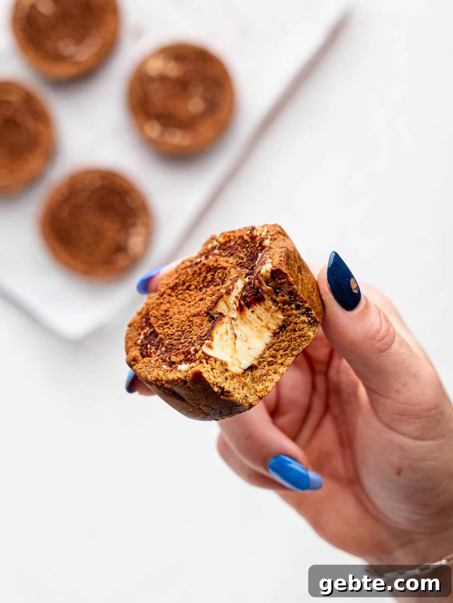 A hand holding a half-eaten Tiramisu cookie dough cup.