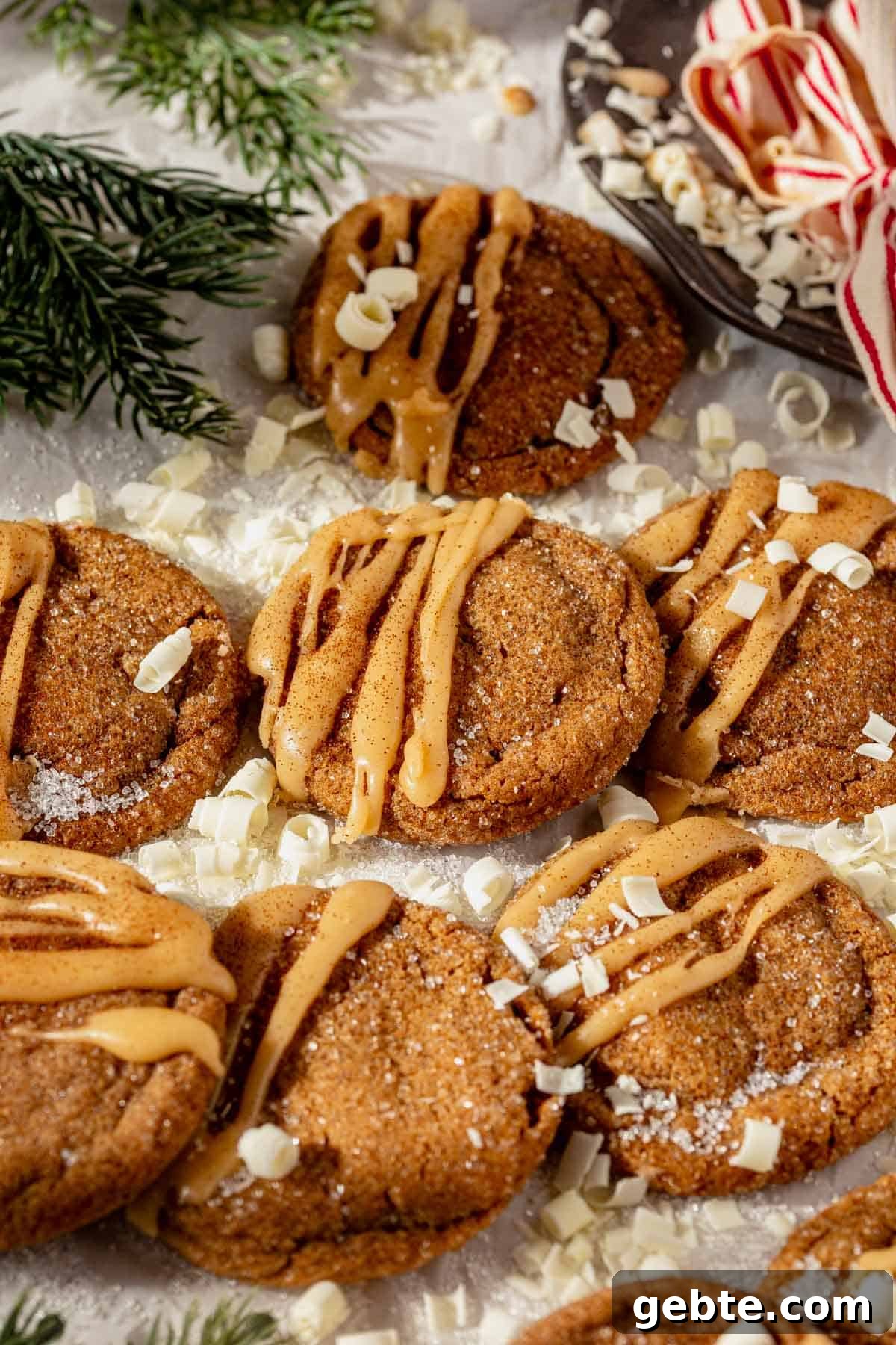 Gingerbread Latte Cookies Recipe — Cozy Spiced Coffee Cookies 3 gingerbread latte cookies with brown butter glaze on a piece of parchment paper with a cup of coffee next to them.