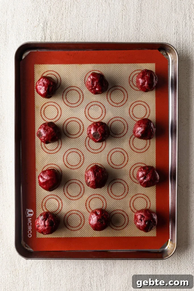 Red Velvet Cake Mix Cookies: Soft, Chewy Cookie Recipe 7 red velvet cake mix cookie dough in balls on a baking mat lined sheet pan