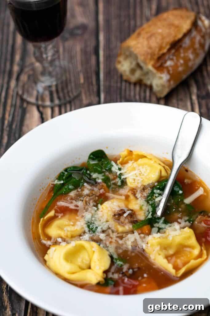 bowl of tuscan tortellini soup with glass of red wine and baguette
