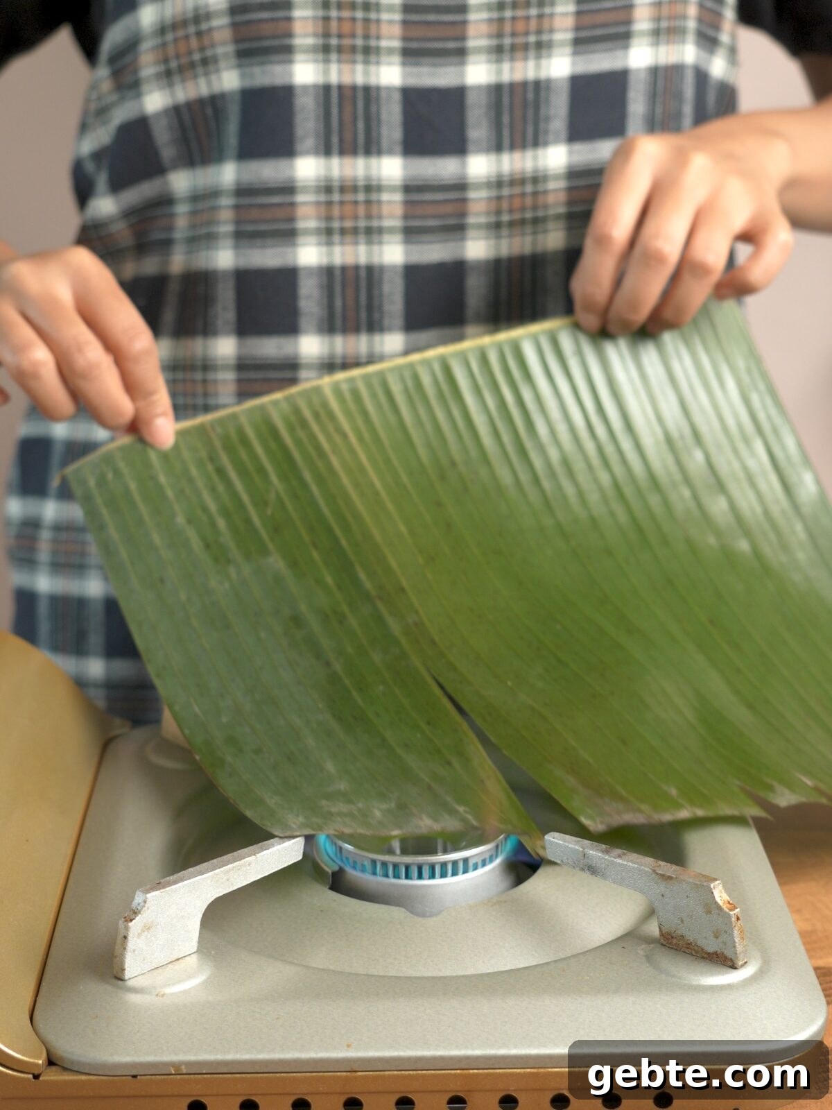 Biko: Filipino Caramelized Sticky Rice Dessert Recipe 7 Banana leaf being dragged over an open flame to release aroma and flavor