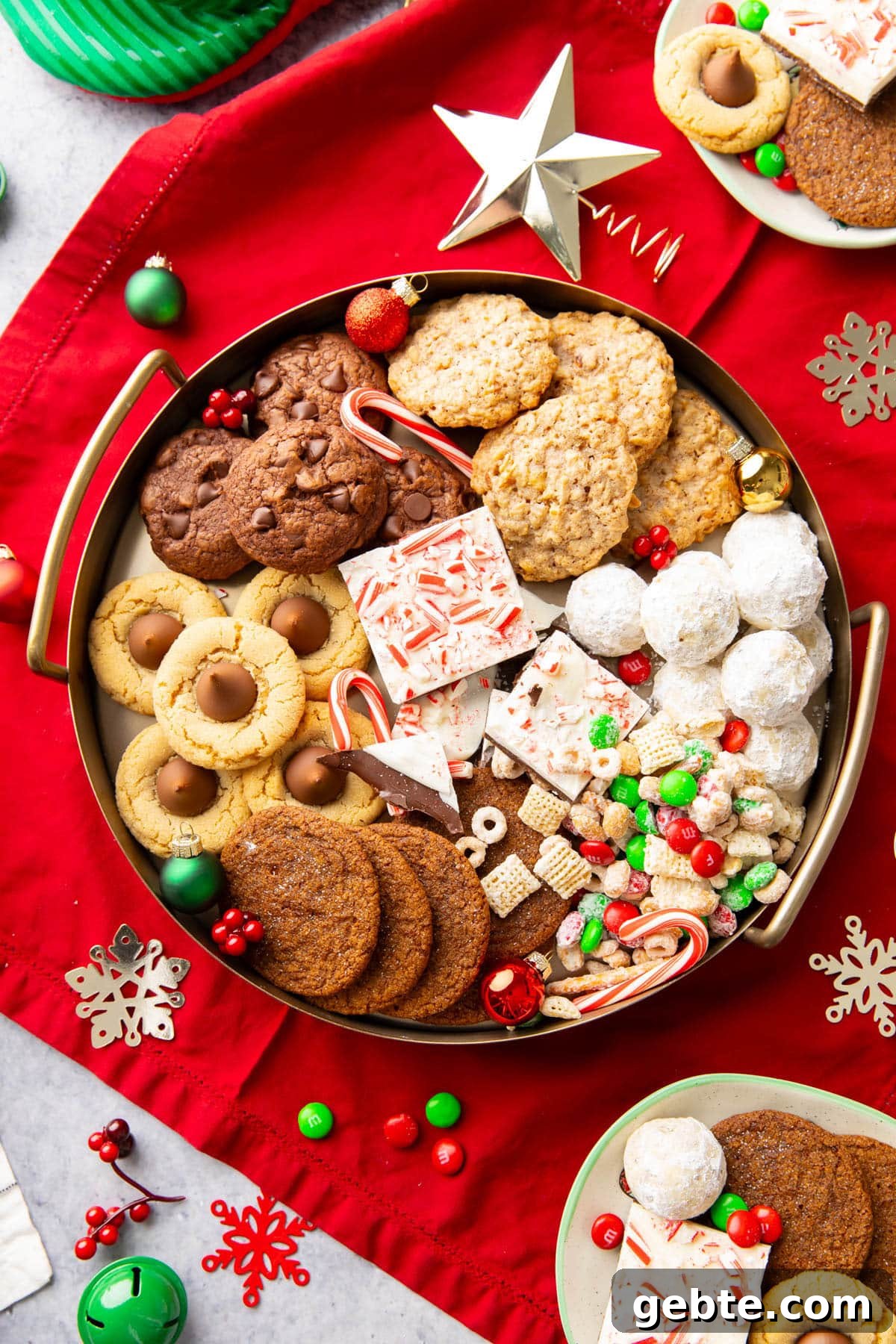 A golden tray filled with Christmas Treats such as peppermint bark, peanut butter blossoms, and snowball cookies.