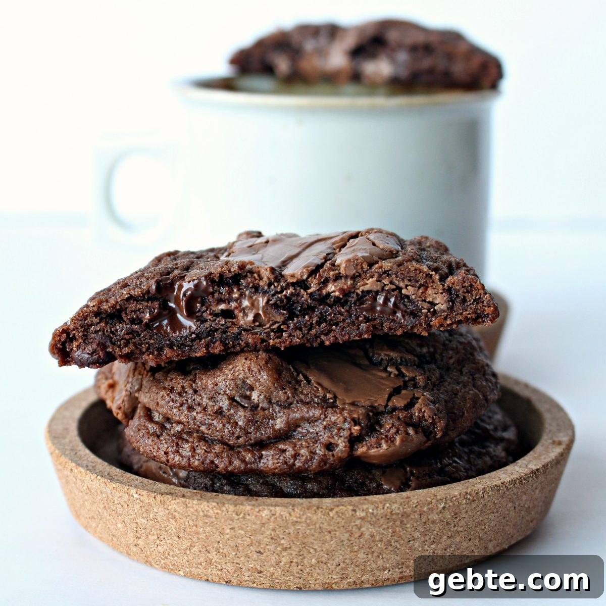 Stack of chocolate cookies with melted chips on a round cork dish.