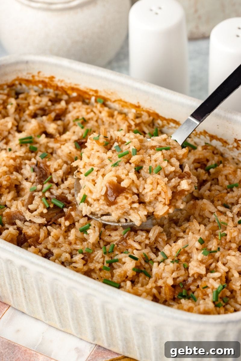 A close-up of Stick of Butter Rice Recipe topped with chopped chives in a white dish.