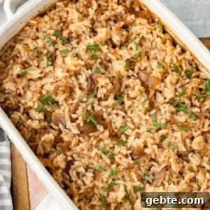 A stick of butter rice in a baking dish, with visible caramelized onions and garnished with chopped chives on top.