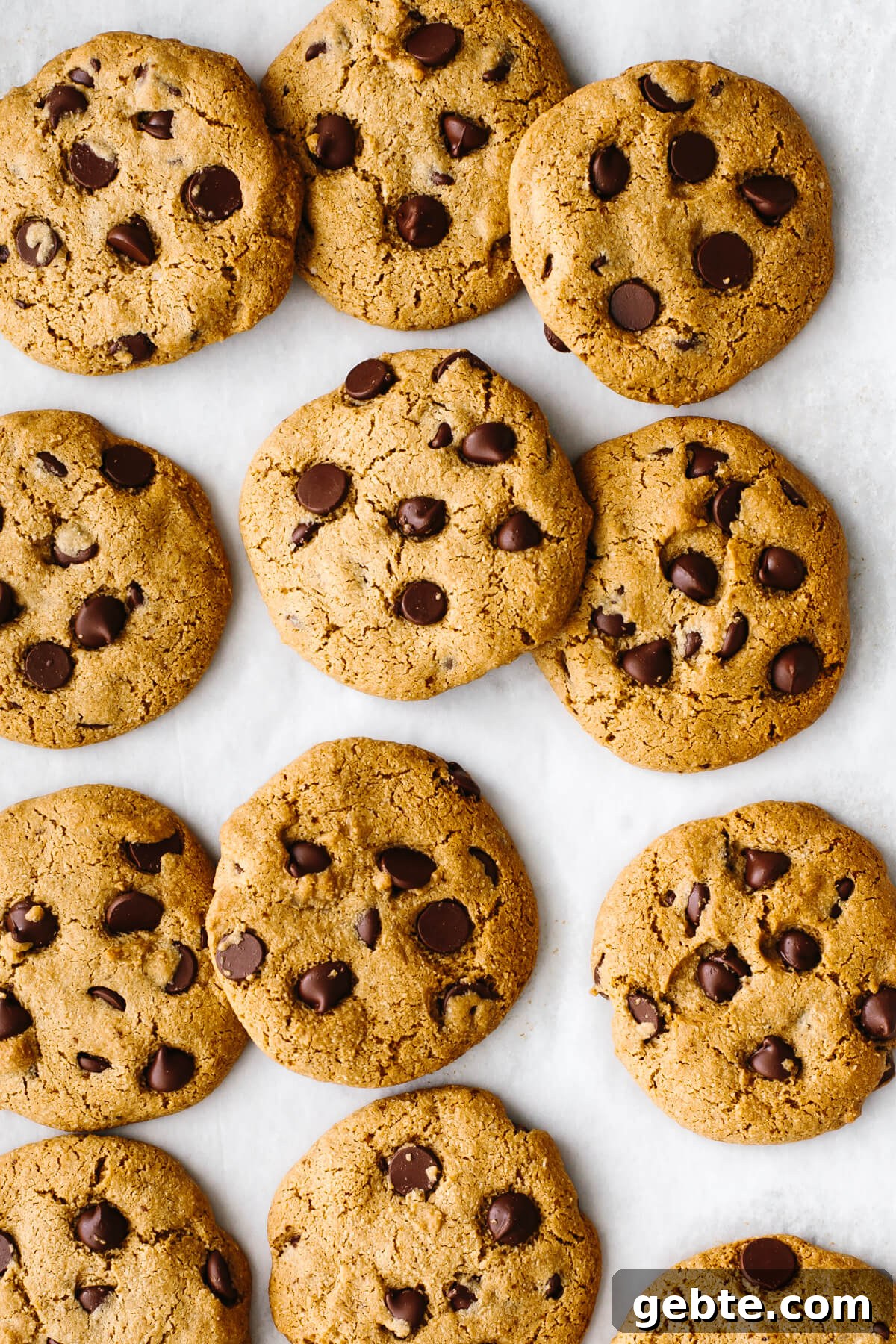 Gluten-free chocolate chip cookies spread out on a baking sheet.