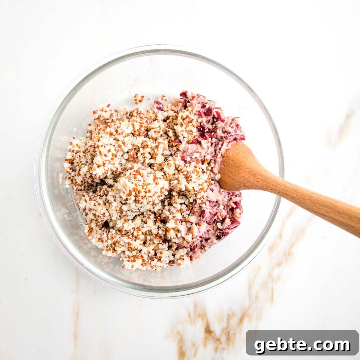 Cooked quinoa and mashed kidney beans in a bowl with wooden spoon.