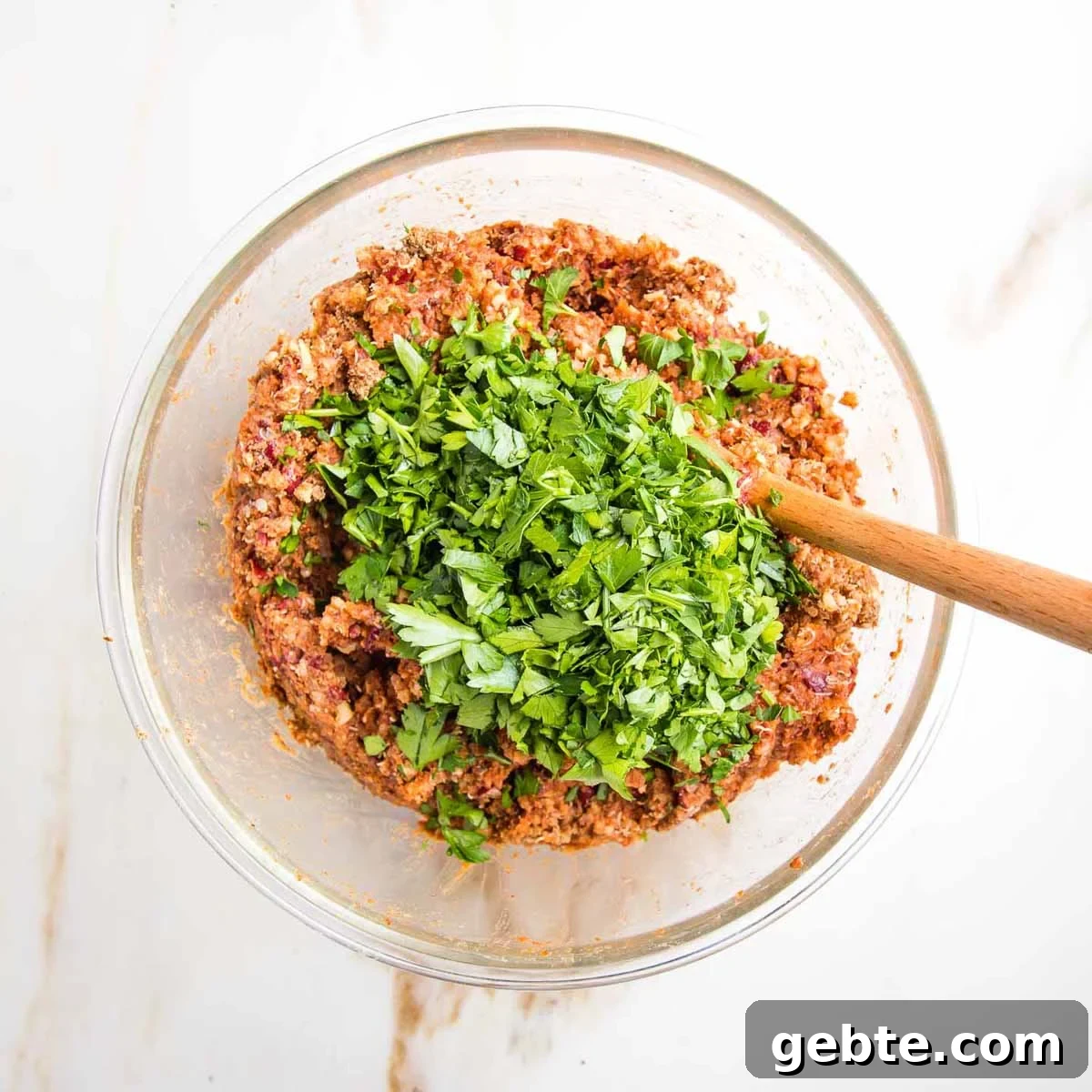 Chopped fresh parsley on top of a veggie burger mixture in a glass bowl.