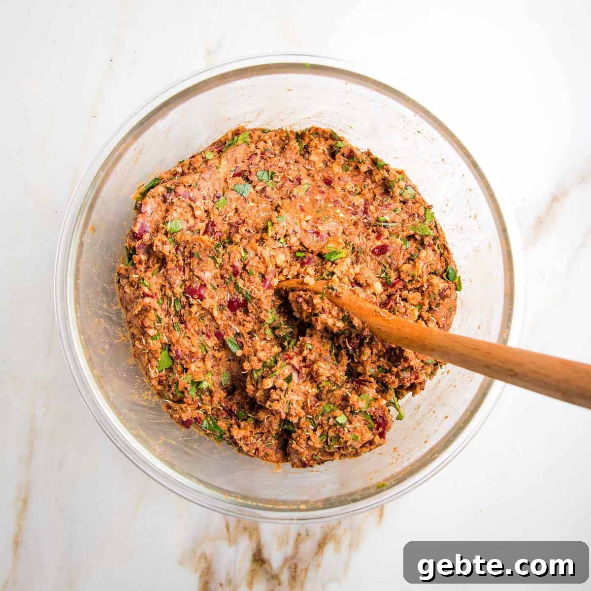 Mashed beans, quinoa, spices and herbs combined to make a veggie burger batter that's brownish red.