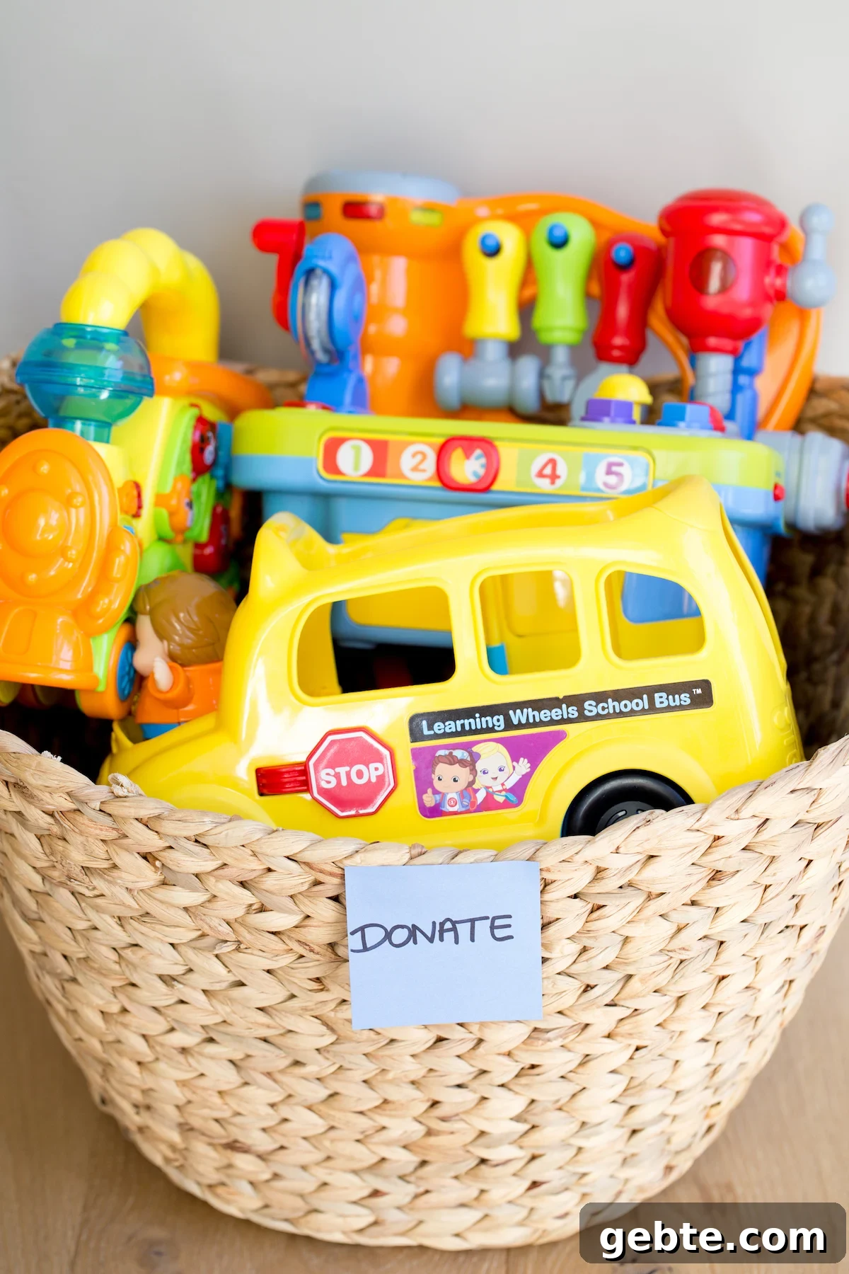 Declutter Toys Quickly: Smart Steps to Organize Kids’ Playroom 7 closeup of plastic toys in a woven basket with a "donate" sticker on it