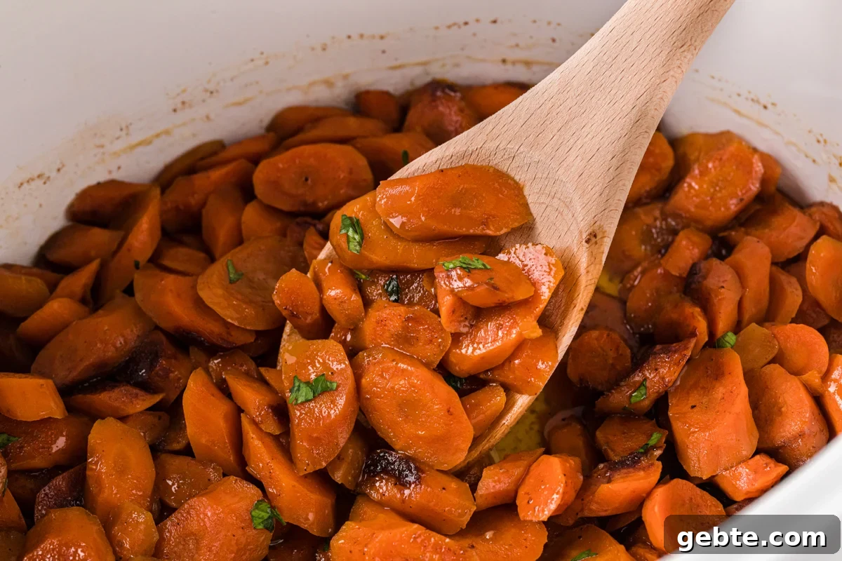 Sliced carrots in a crockpot with a wooden spoon scooping some out.